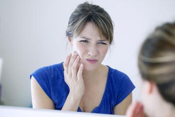 Woman touching her pained jaw in a Palatine mirror